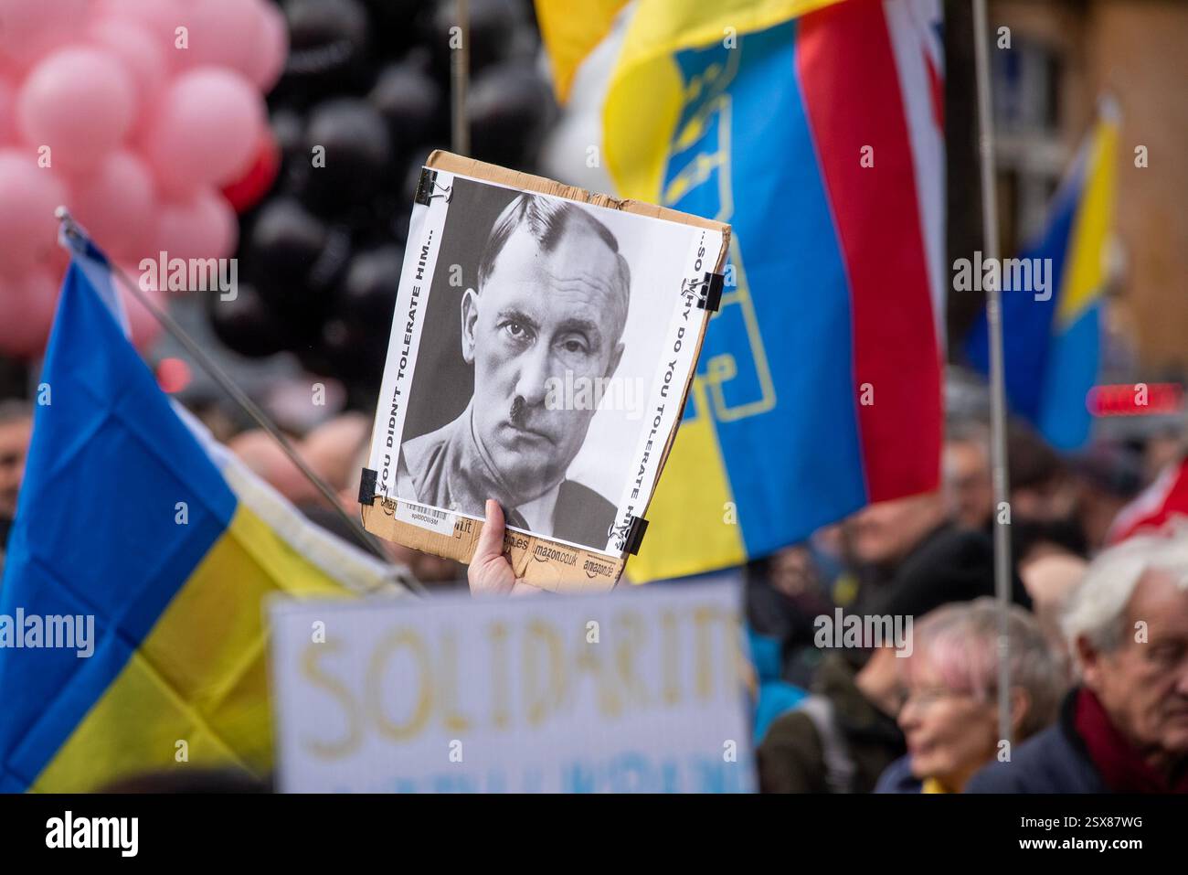 London, Großbritannien. Februar 2025. Ein Demonstrant hält ein Schild mit einem Foto. Es zeigt das Halbgesicht von Wladimir Putin und das andere Halbgesicht von Adolf Hitler während der Demonstration. Hunderte Ukrainer und Unterstützer versammelten sich an der Statue des Heiligen Wolodymyr. Nur zwei Tage vor dem dritten Jahrestag der russischen Invasion auf die Ukraine. Die Demonstranten marschierten vom Denkmal des heiligen Wolodymyr dem Großen zur russischen Botschaft. Quelle: SOPA Images Limited/Alamy Live News Stockfoto