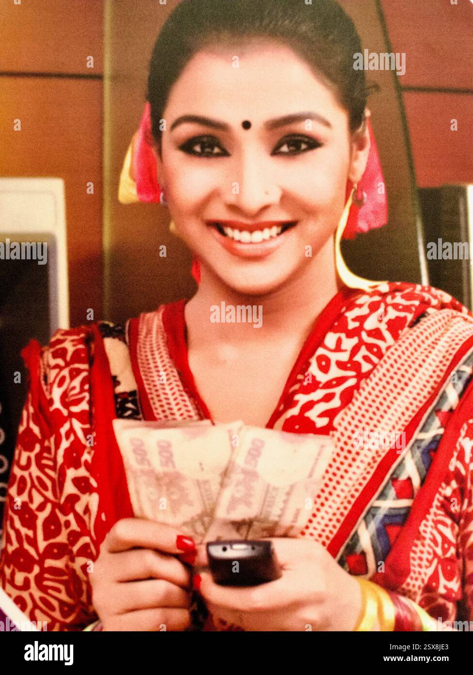 Frau zeigt Bangladeschische Währung per Handy an und hebt den einfachen Bargeldzugang über die mobile Bankplattform Rocket der Dutch-Bangla Bank hervor. Stockfoto