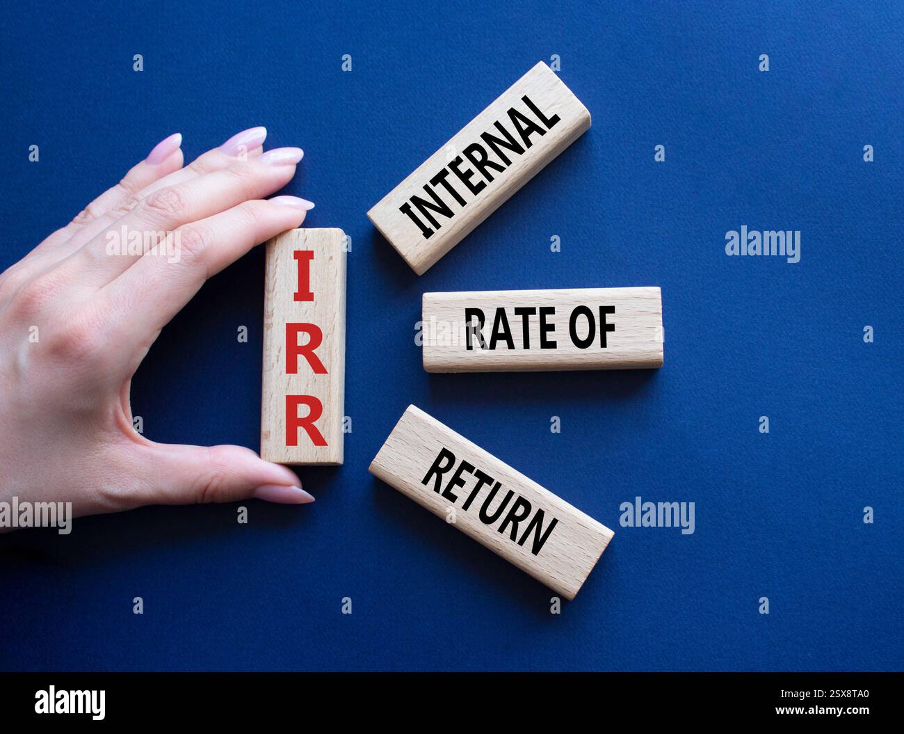 IRR – Symbol für interne Rückkehrrate. Konzeptwort IRR auf Holzwürfeln. Geschäftsmann Hand. Wunderschöner tiefblauer Hintergrund. Business und IRR-Konzept. Co Stockfoto