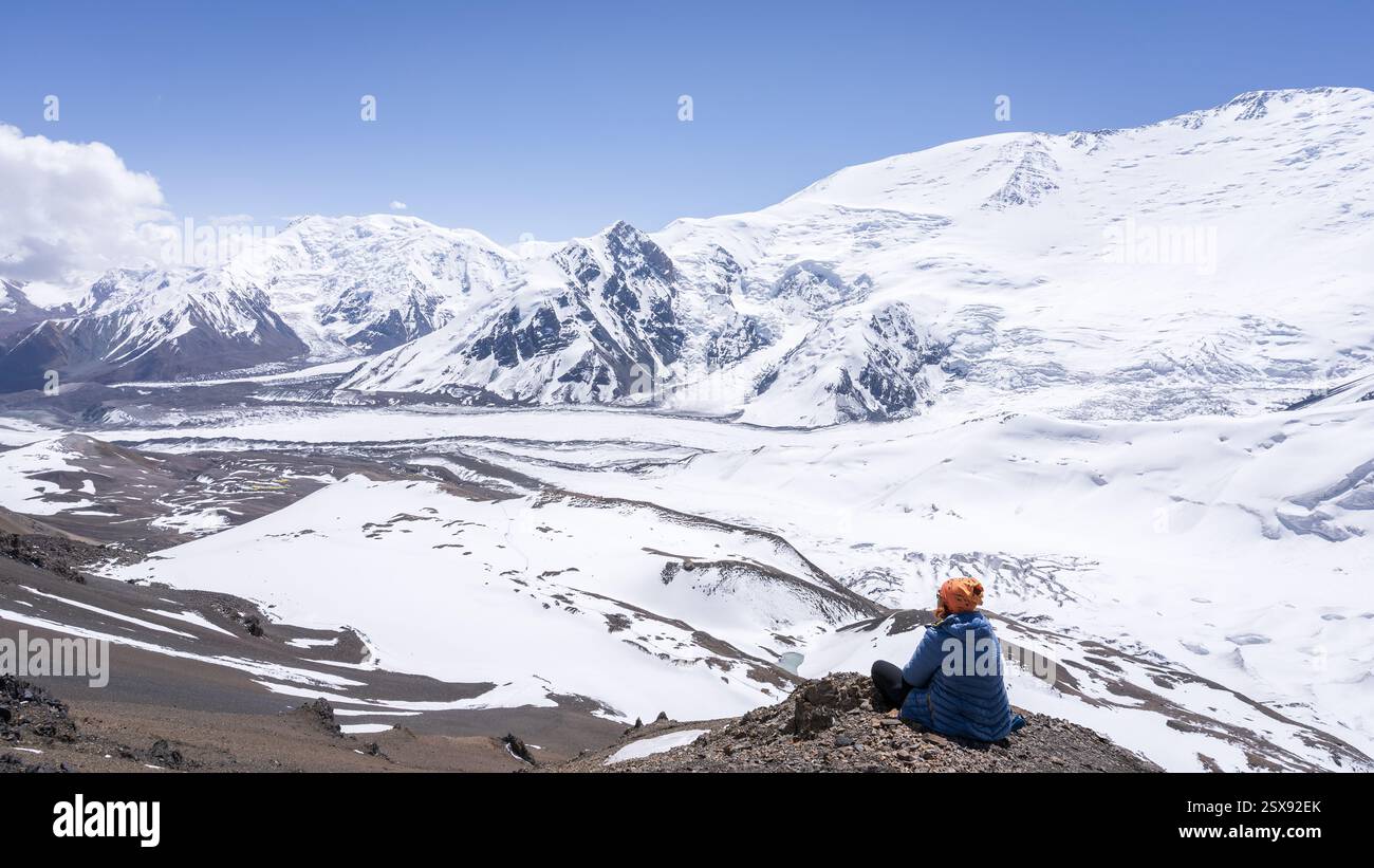 Frau genießt Aussicht auf das wunderschöne Gletschertal und die schneebedeckten Gipfel um sie herum, Pamir, Kirgisistan. Stockfoto