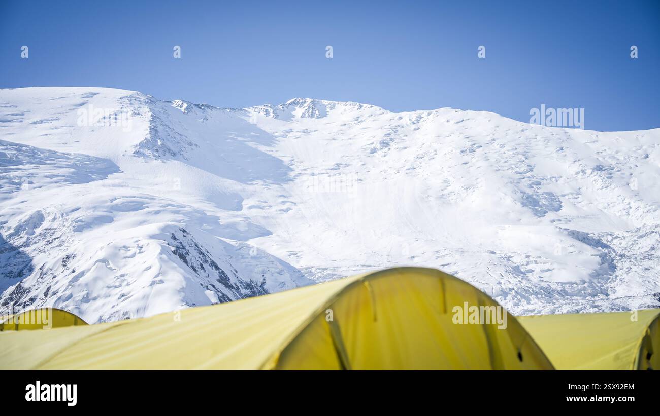 Expeditionszelte im Bergsteigercamp mit schneebedecktem Bergkamm, hoch oben in Pamir, Kirgisistan. Stockfoto