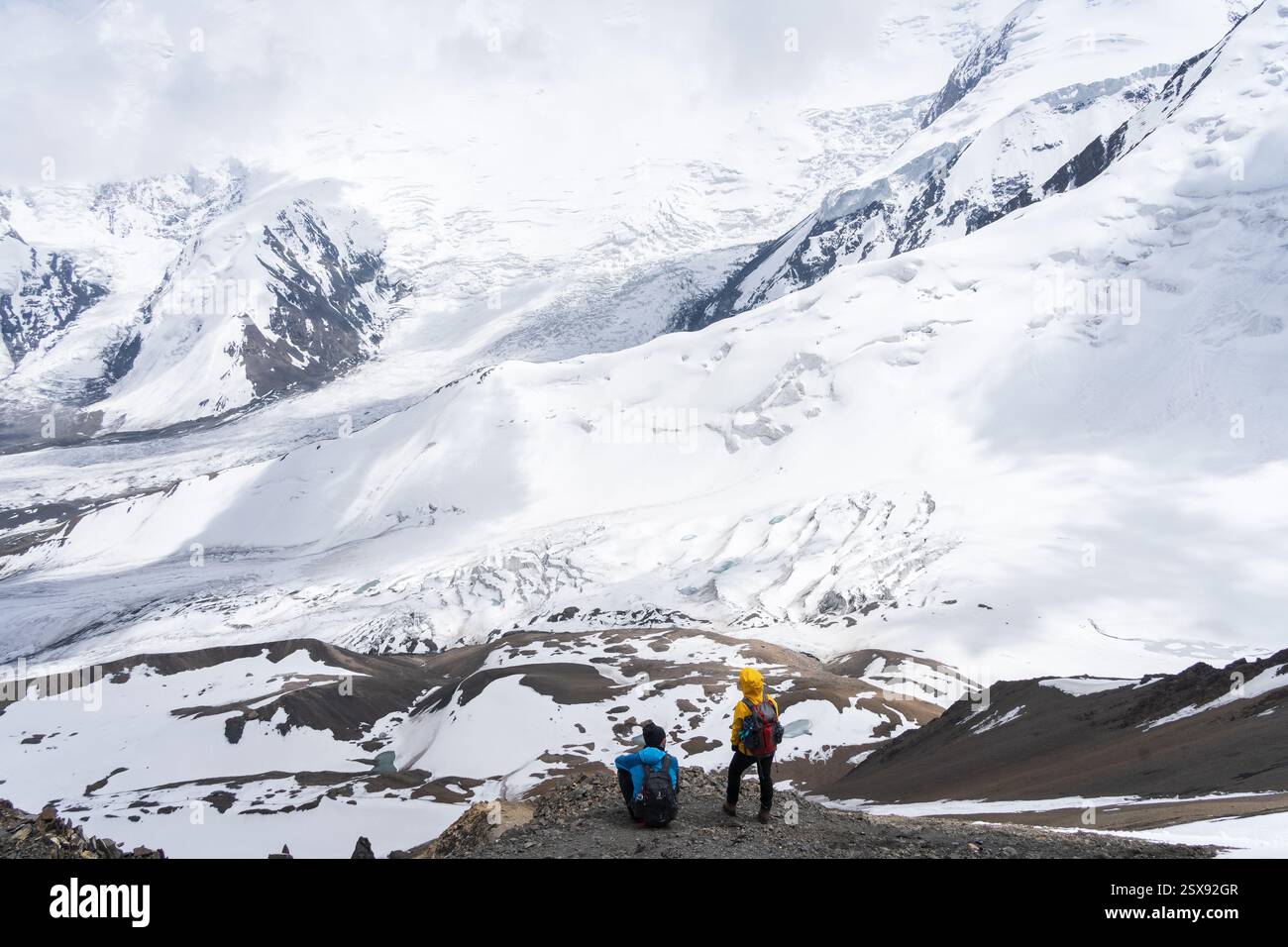 Mann und Frau genießen die Aussicht auf die Alpen- und Gletscherlandschaft vor ihnen, Pamir, Kirgisistan. Stockfoto