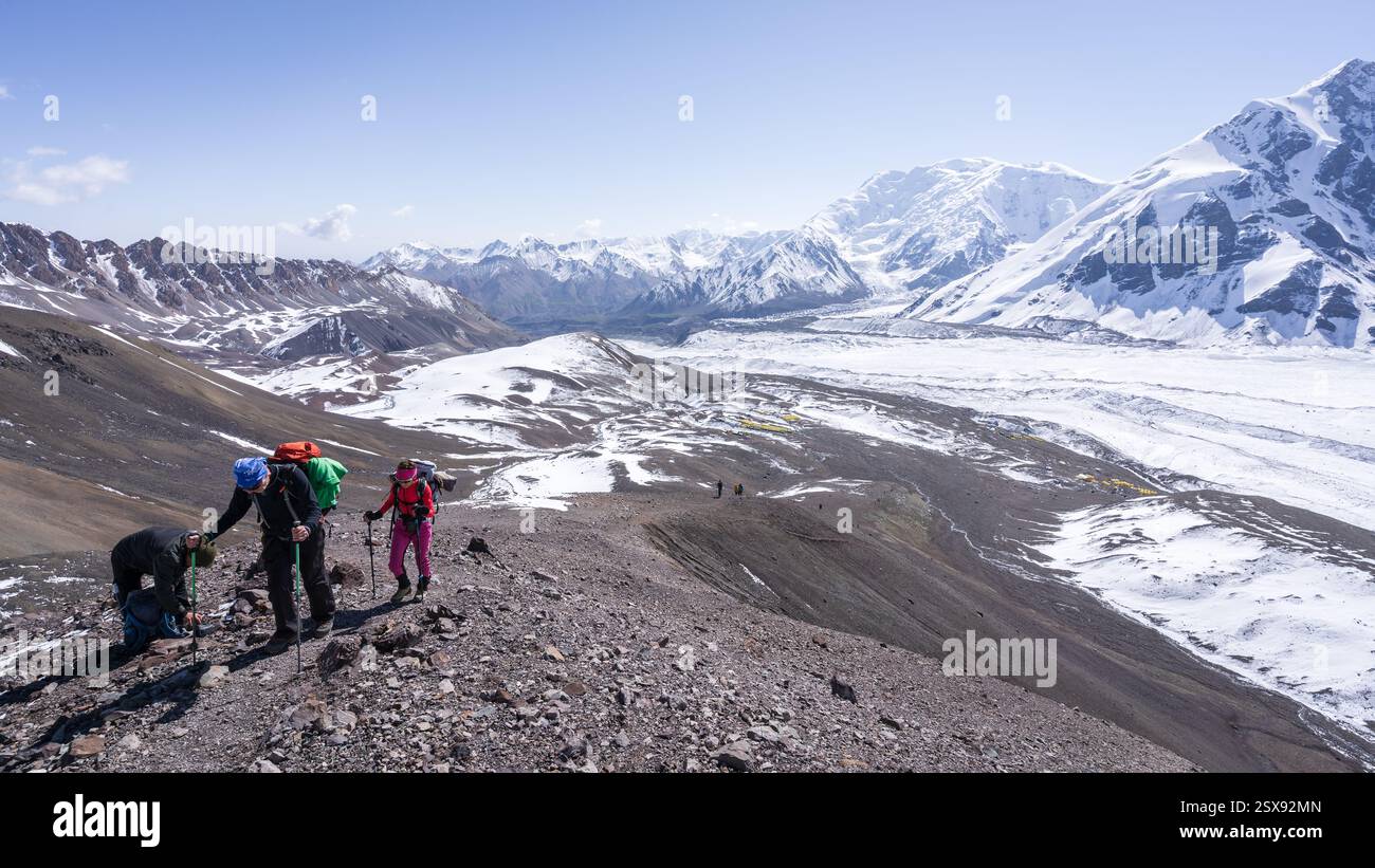 Ältere Ehepaare wandern bergauf mit wunderschöner alpiner Landschaft dahinter, Pamir Mountains, Kirgisistan Stockfoto