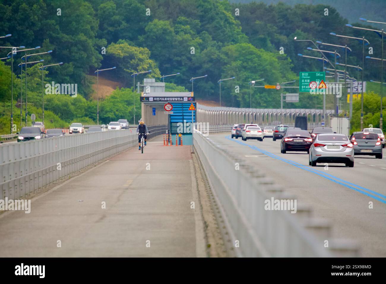 Daejeon, Südkorea - 28. Mai 2021: Radfahrer fahren auf dem speziellen Radweg auf der North Star Road, der durch Leitplanken vom Autobahnverkehr getrennt ist. Stockfoto