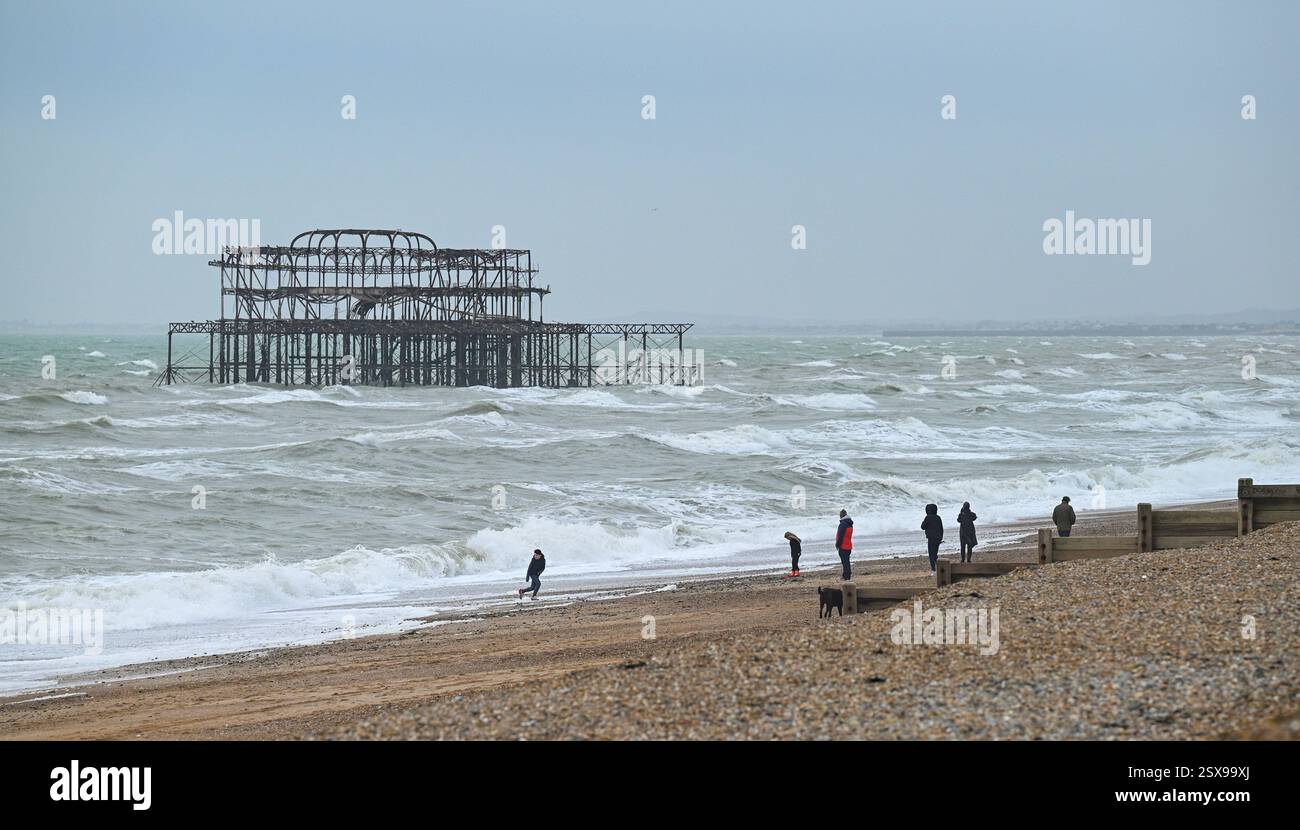 Brighton UK 23. Februar 2025 - Walkers Genießen Sie das windige Wetter am Brighton Beach heute : Credit Simon Dack / Alamy Live News Stockfoto