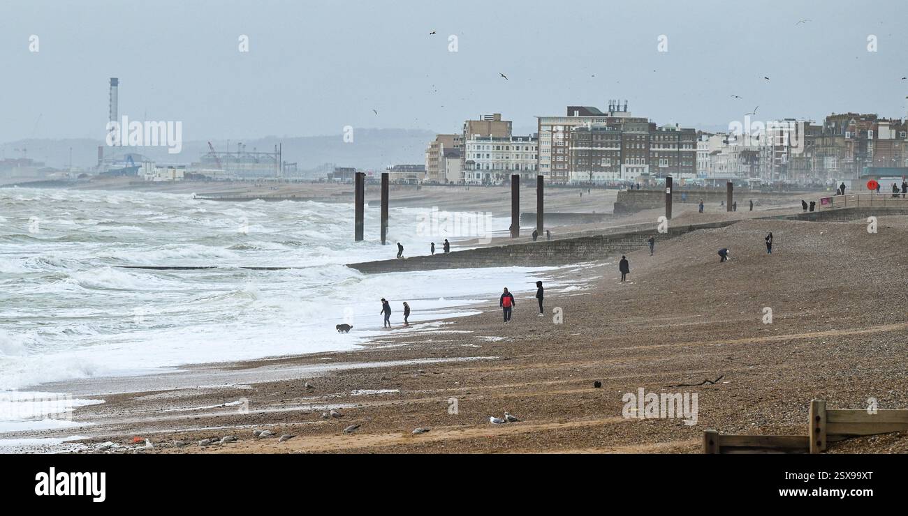 Brighton UK 23. Februar 2025 - Walkers Genießen Sie das windige Wetter am Brighton Beach heute : Credit Simon Dack / Alamy Live News Stockfoto