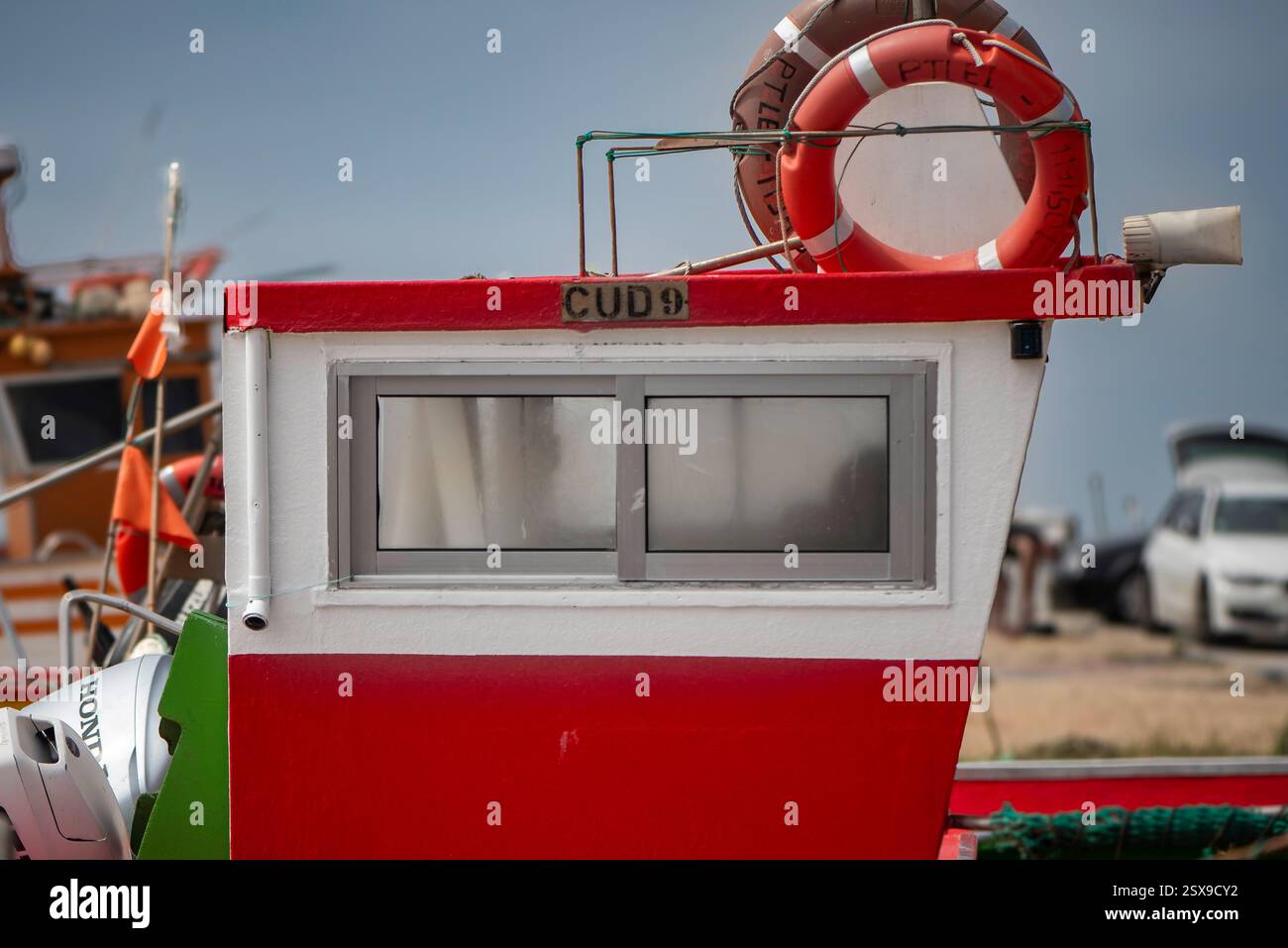 Seitenansicht einer rot-weißen Bootskabine mit Rettungsschirm und Ausrüstung, die an einem Sandstrand mit anderen Schiffen im Hintergrund angedockt ist Stockfoto