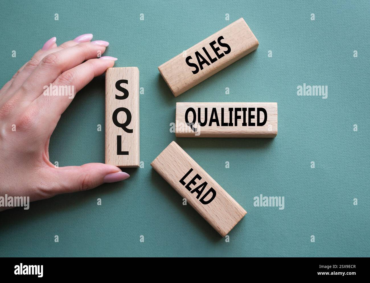 SQL - qualifizierter Lead für Vertrieb. Holzwürfel mit SQL-Wörtern. Geschäftsmann Hand. Wunderschöner graugrüner Hintergrund. Business- und SQL-Konzept. Kopierbereich. Stockfoto