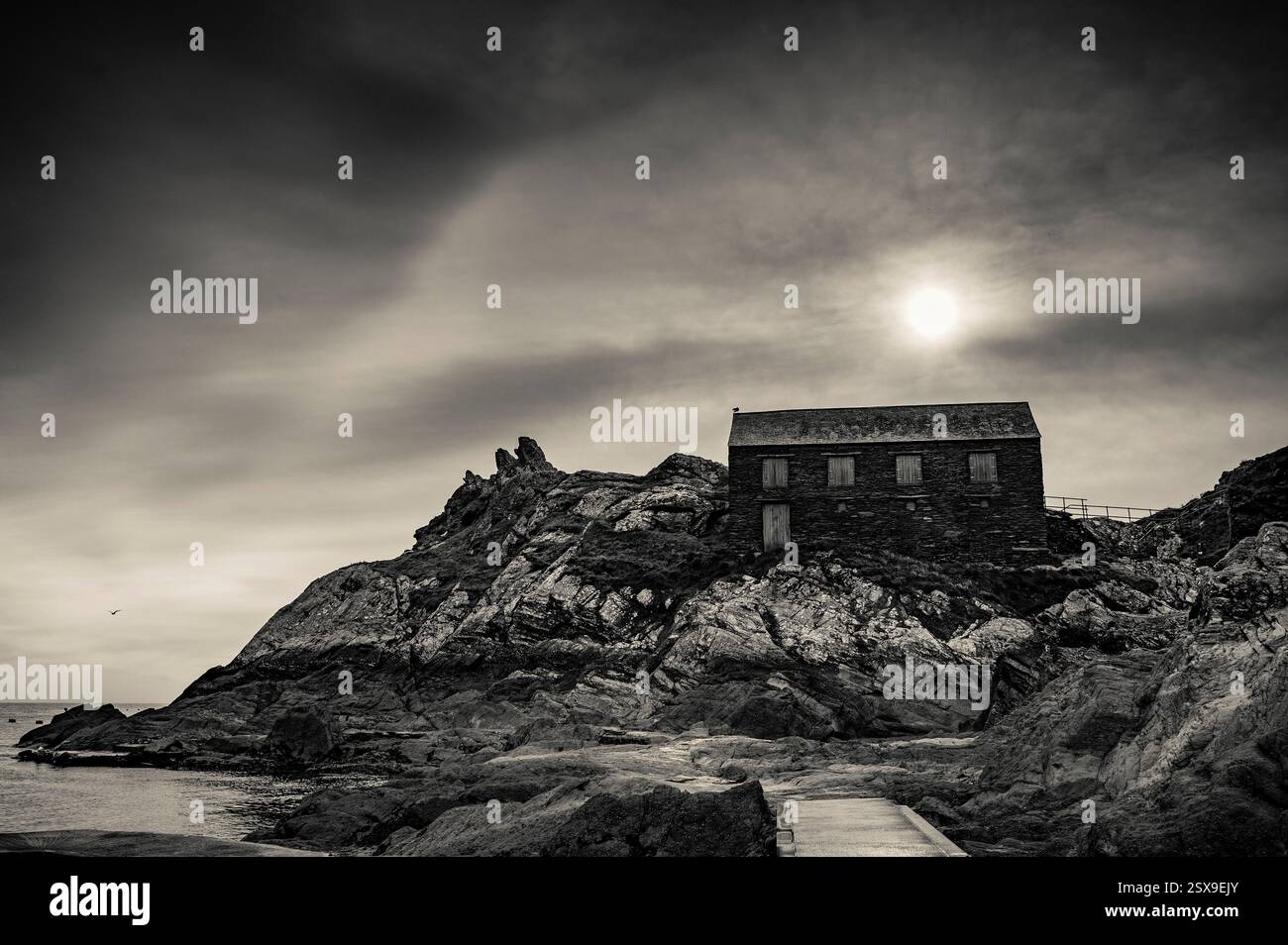 Sun Over Peak Rock & The Net Loft ein denkmalgeschütztes Gebäude, Polperro, Cornwal, l UK Schwarzweißfoto Stockfoto
