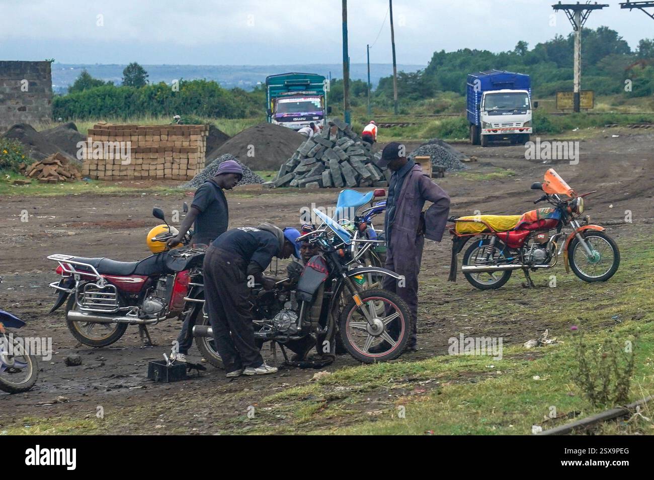 Daily Life in Gilgil, Kenia Männer arbeiten am 30. Januar 2025 an einem Motorrad an einem Straßenrand in Gilgil, Kenia. Gilgil ist eine kleine, aber lebendige Stadt im Nakuru County, Kenia, am Rande des Great Rift Valley. Gilgil ist traditionell für seine landwirtschaftlichen Wurzeln bekannt und hat sich zunehmend zu einem Drehkreuz für Kleinunternehmen entwickelt, was die umfassenderen wirtschaftlichen Veränderungen in Kenia widerspiegelt. Lokale Unternehmer nutzen die robuste Telekommunikationsinfrastruktur der Nationen, die für Innovationen wie mobile Gelddienste bekannt ist, um sich mit breiteren Märkten zu verbinden und den Betrieb zu optimieren. Diese digitale Transformi Stockfoto