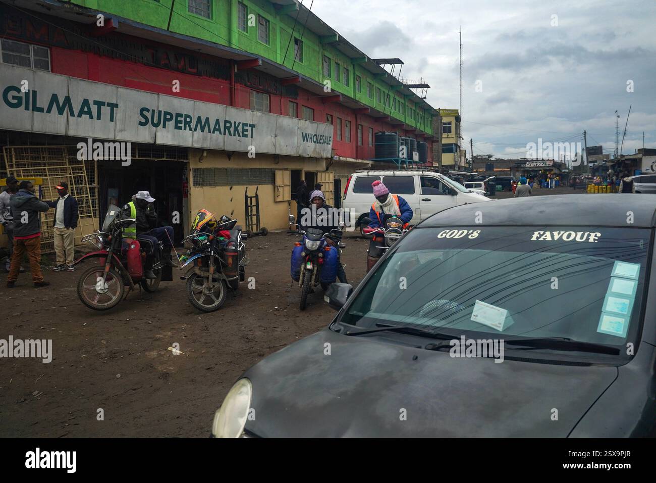Das tägliche Leben in Gilgil, Kenia Männer ruhen sich am 30. Januar 2025 auf geparkten Motorrädern vor dem Gilmatt Supermarkt in Gilgil, Kenia aus. Gilgil ist eine kleine, aber lebendige Stadt im Nakuru County, Kenia, am Rande des Great Rift Valley. Gilgil ist traditionell für seine landwirtschaftlichen Wurzeln bekannt und hat sich zunehmend zu einem Drehkreuz für Kleinunternehmen entwickelt, was die umfassenderen wirtschaftlichen Veränderungen in Kenia widerspiegelt. Lokale Unternehmer nutzen die robuste Telekommunikationsinfrastruktur der Nationen, die für Innovationen wie mobile Gelddienste bekannt ist, um sich mit breiteren Märkten zu verbinden und den Betrieb zu optimieren. Dies Stockfoto