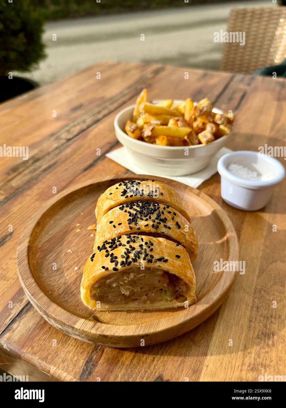 Hausgemachter Dorset Apfel und Wurstbrötchen serviert mit Chips und Meersalz - Smartphone-aufgenommenes Stockfoto