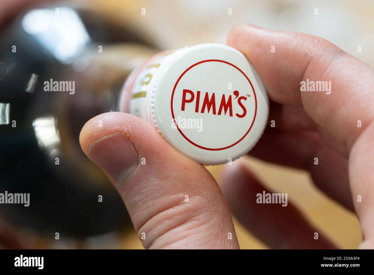 Man's Hand, die einen Schraubverschluss auf eine Flasche Pimm's aufschraubt, eine englische Marke von Obstbecher auf Gin-Basis, die auch als Likör oder Basis eines Punschs angesehen wird, Großbritannien Stockfoto