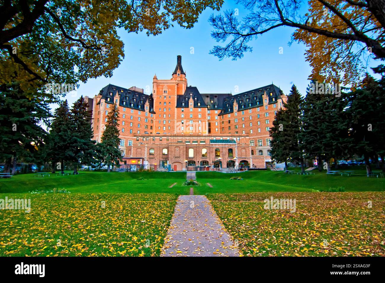 Großes Gebäude mit grünem Dach und gelber Fassade. Das Gebäude ist von Bäumen umgeben und hat einen großen Innenhof davor. Der Innenhof ist Stockfoto