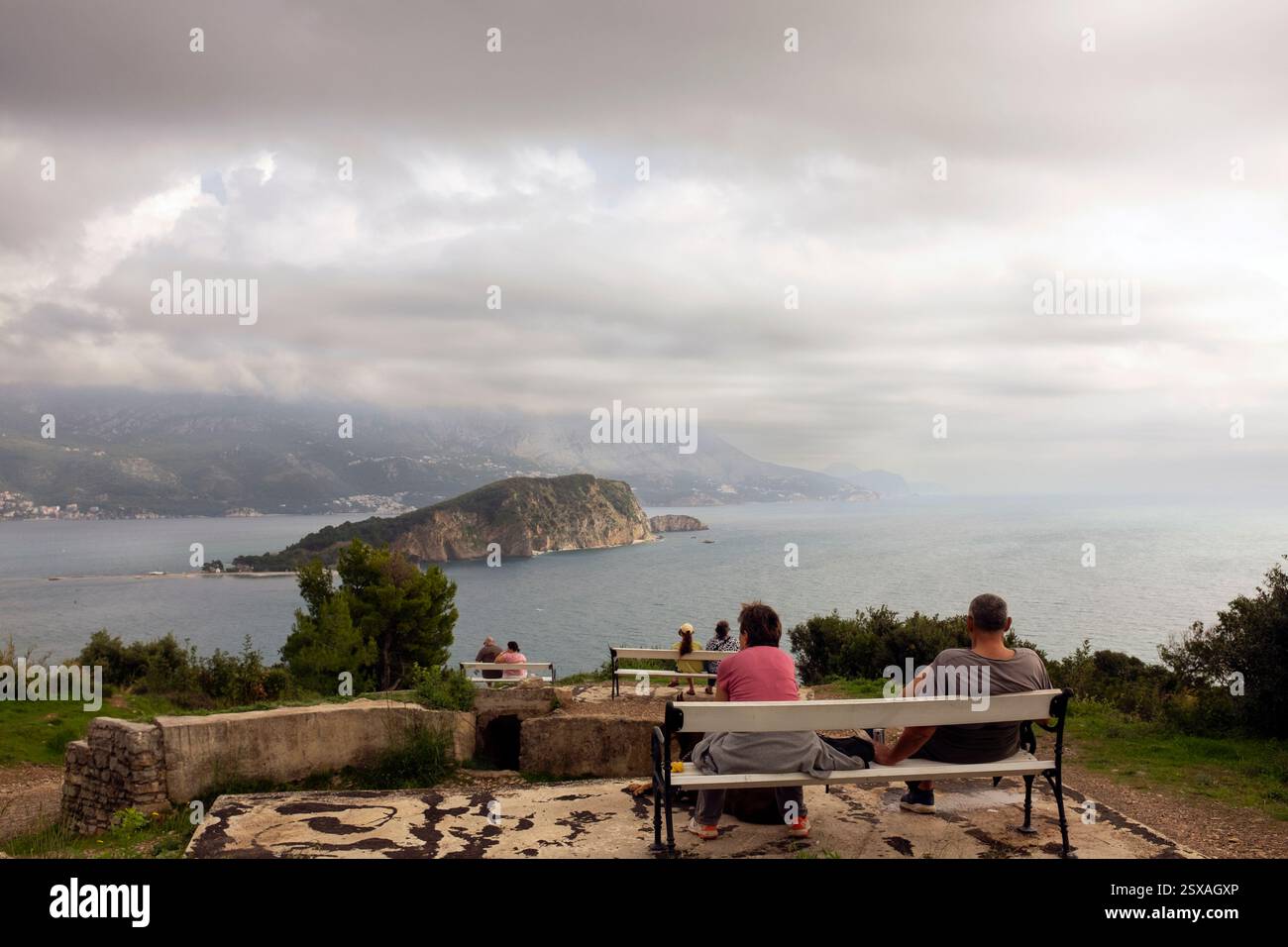 Menschen genießen die Aussicht auf die Insel Sveti Nikola von Fort Mogren, Budva, Montenegro Stockfoto