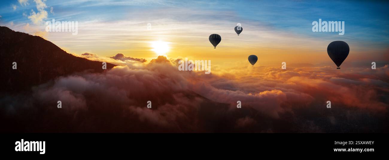Heißluftballons fliegen über Berge und Wolken bei Sonnenuntergang Stockfoto