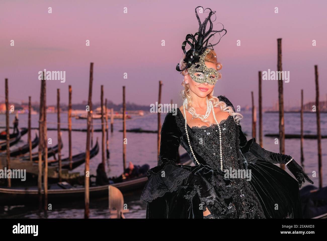 Venezianischer Karneval, Frau im eleganten venezianischen Ballkleid Kostüm posiert bei Sonnenuntergang an der Lagune, Venezia, Italien Stockfoto