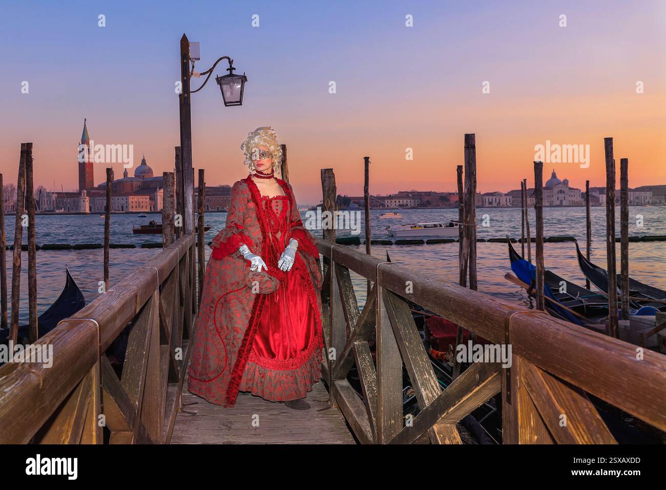 Venezianischer Karneval, Frau im eleganten venezianischen Ballkleid Kostüm posiert bei Sonnenuntergang an der Lagune, Venezia, Italien Stockfoto