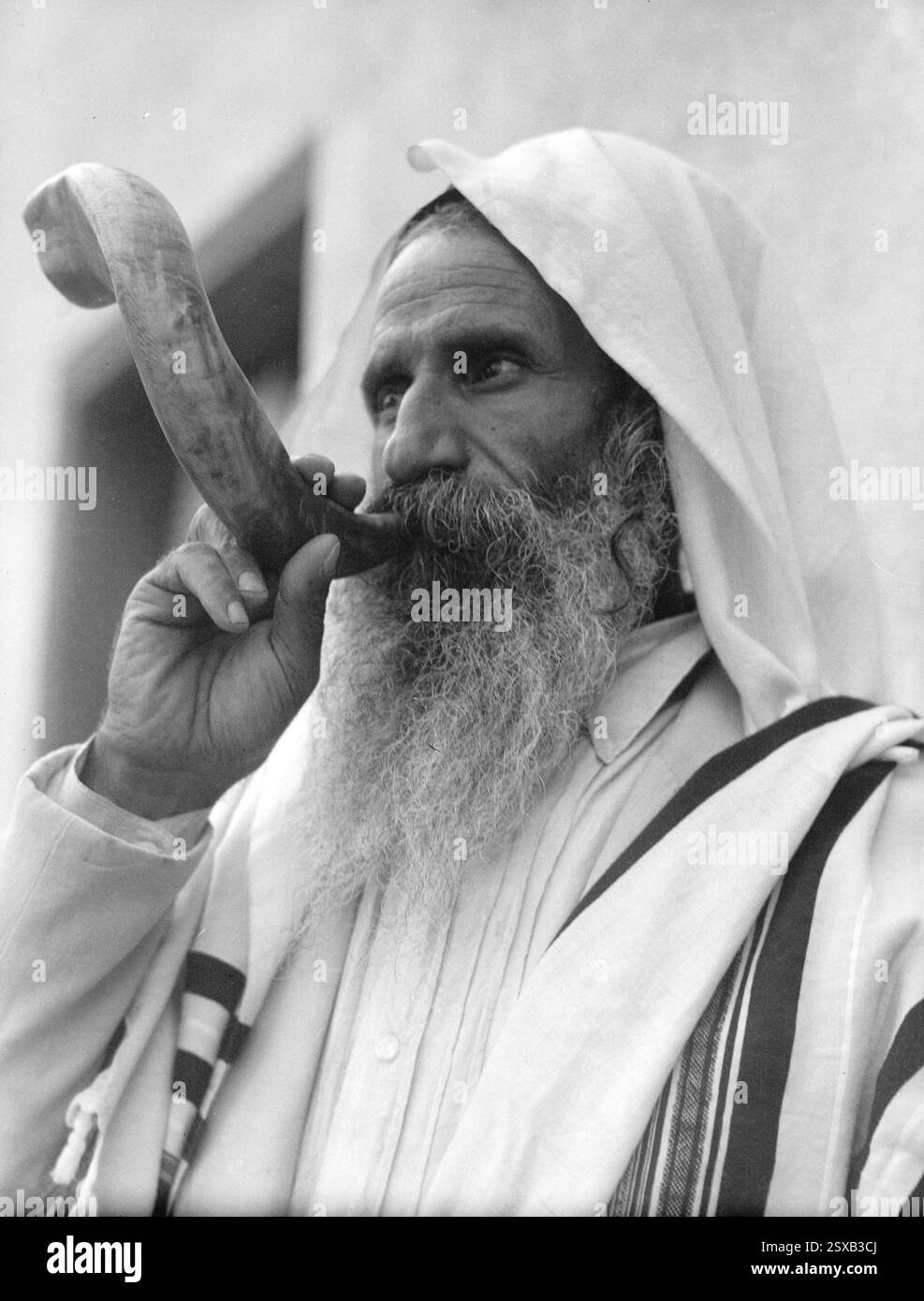 Jüdischer Mann, der einen Schofar bläst, eine Widderhorntrompete, die früher von Juden als altes Kampfsignal verwendet wurde und heute in jüdischen religiösen Zeremonien verwendet wird.1930er Jahre Stockfoto