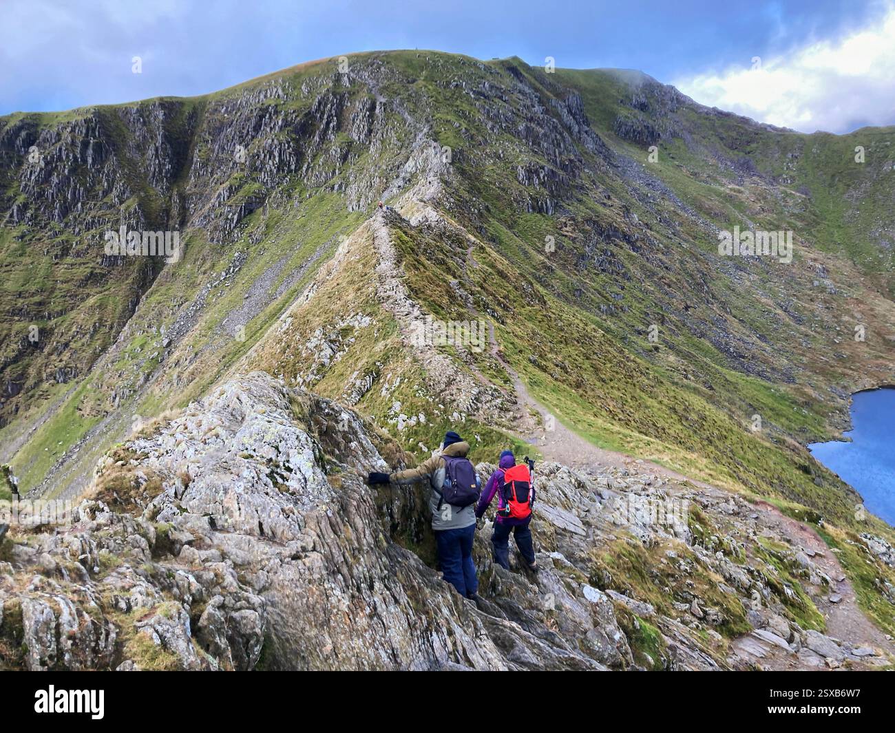 Wanderer, die über den Kamm des Striding Edge klettern und versuchen, den Gipfel des Helvellyn Mountain vor sich zu erreichen, den Lake District, England, Großbritannien - Smartphone-aufgenommenes Stockfoto