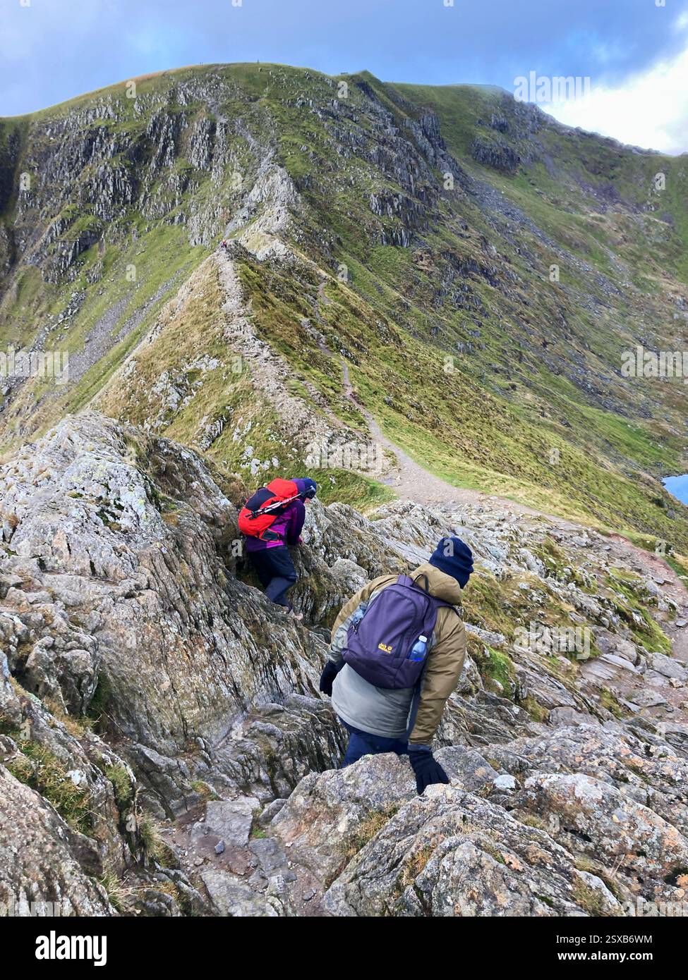 Wanderer, die über den Kamm des Striding Edge klettern und versuchen, den Gipfel des Helvellyn Mountain vor sich zu erreichen, den Lake District, England, Großbritannien - Smartphone-aufgenommenes Stockfoto