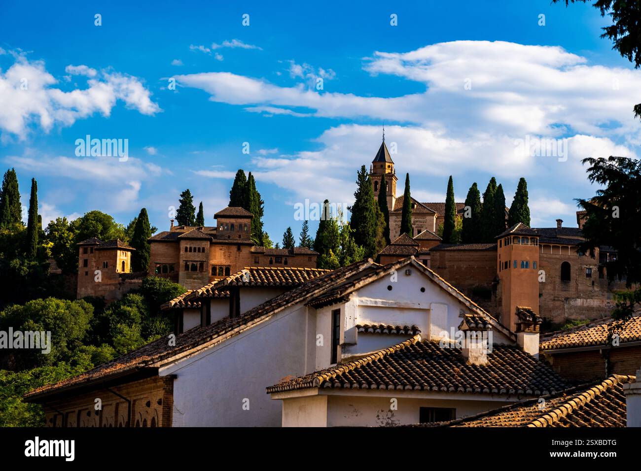 Die maurische Alhambra über den Dächern Granadas: Jahrhundertelange nasridische Pracht inmitten grüner andalusischer Zypressen-Silhouetten und zeitlosem spanischem Erbe Stockfoto