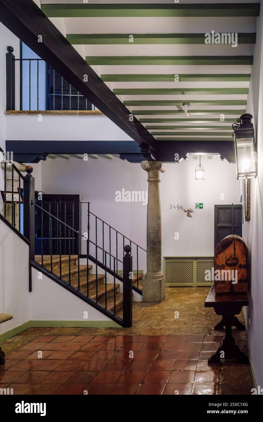 Klassischer Flur mit antik rotem Fliesenboden, Holzbalkendecke und Treppe mit antikem Eisengeländer im Parador de Turismo in Almagro, Spanien. Stockfoto