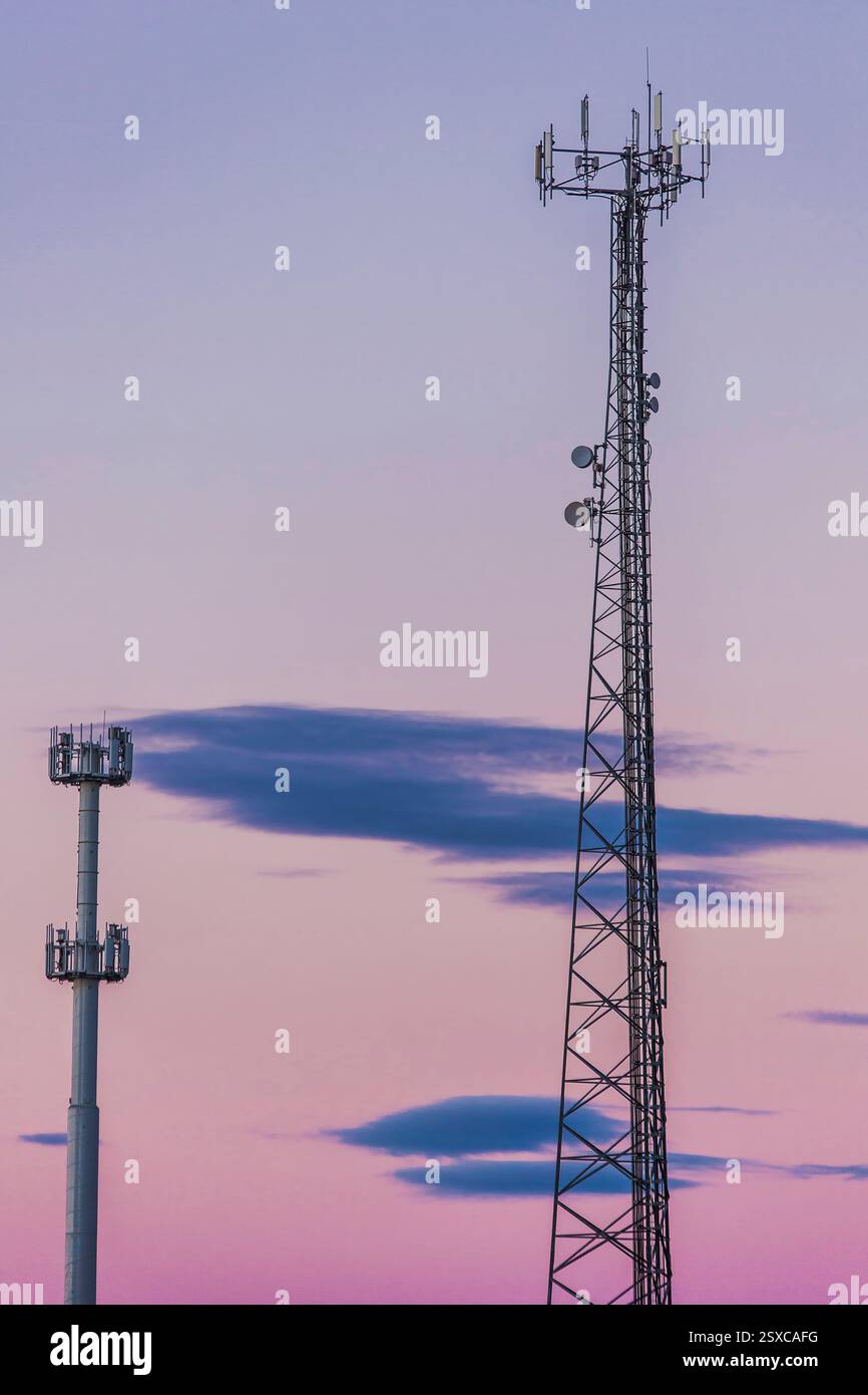Zwei hohe Türme mit Antennen oben. Einer ist größer als der andere. Der Himmel ist rosa und lila Stockfoto