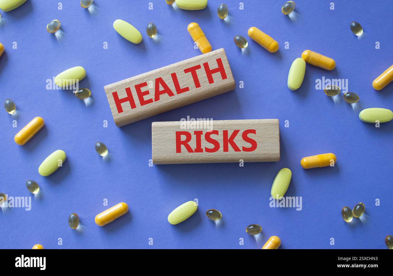 Symbol für Gesundheitsrisiken. Konzeptwort Gesundheitsrisiken auf Holzklötzen. Schöner lila Hintergrund mit Pillen. Medizin und Gesundheitsrisiko-Konzept. Kopierbereich Stockfoto
