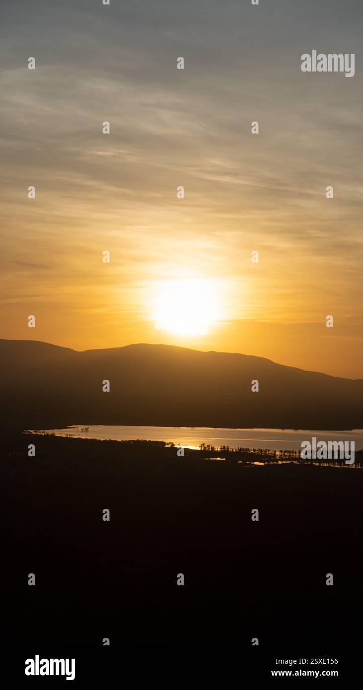 Erleben Sie einen atemberaubenden Sonnenuntergang, der die ruhigen Hügel und das Wasser im atemberaubenden Colors Lake Manyara Tansania Afrika zeigt Stockfoto