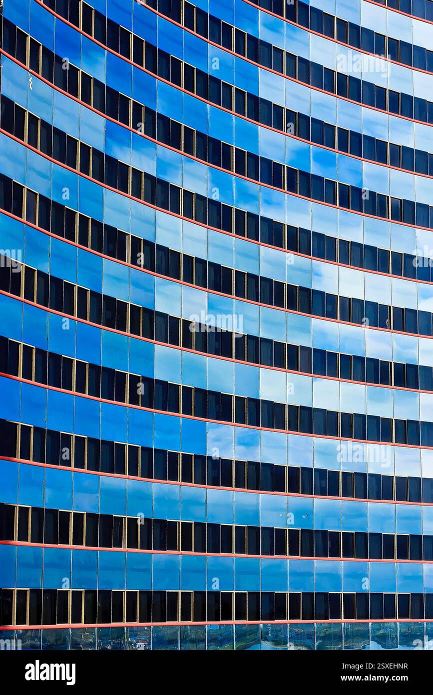 Das blaue Gebäude hat viele Fenster und ein sehr modernes Aussehen. Die blaue Farbe des Gebäudes ist sehr auffällig und hebt sich vom Himmel ab Stockfoto