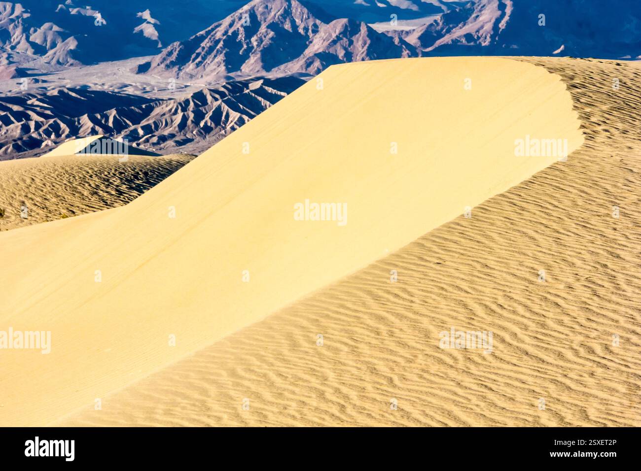 Sandiger Hügel mit einem Berg im Hintergrund. Der Hügel ist mit Sand bedeckt und hat eine leichte Steigung Stockfoto