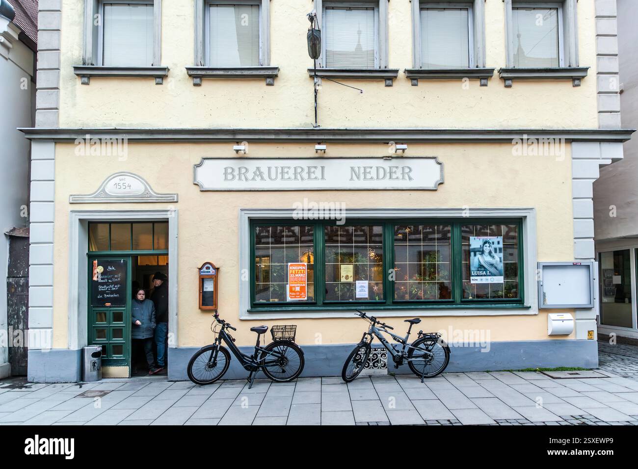 Die Neder Brauerei in der Forchheimer Altstadt begrüßt Gäste unter dem Schriftzug „Brauerei Neder“ über dem Eingang, wobei zwei Fahrräder an der cremefarbenen Fassade lehnen. Die Brauerei wurde erstmals 1554 urkundlich erwähnt und gilt als die älteste noch betriebene Brauerei in Forchheim. St.-Martin-Straße, Forchheim, Bayern, Deutschland. Stockfoto