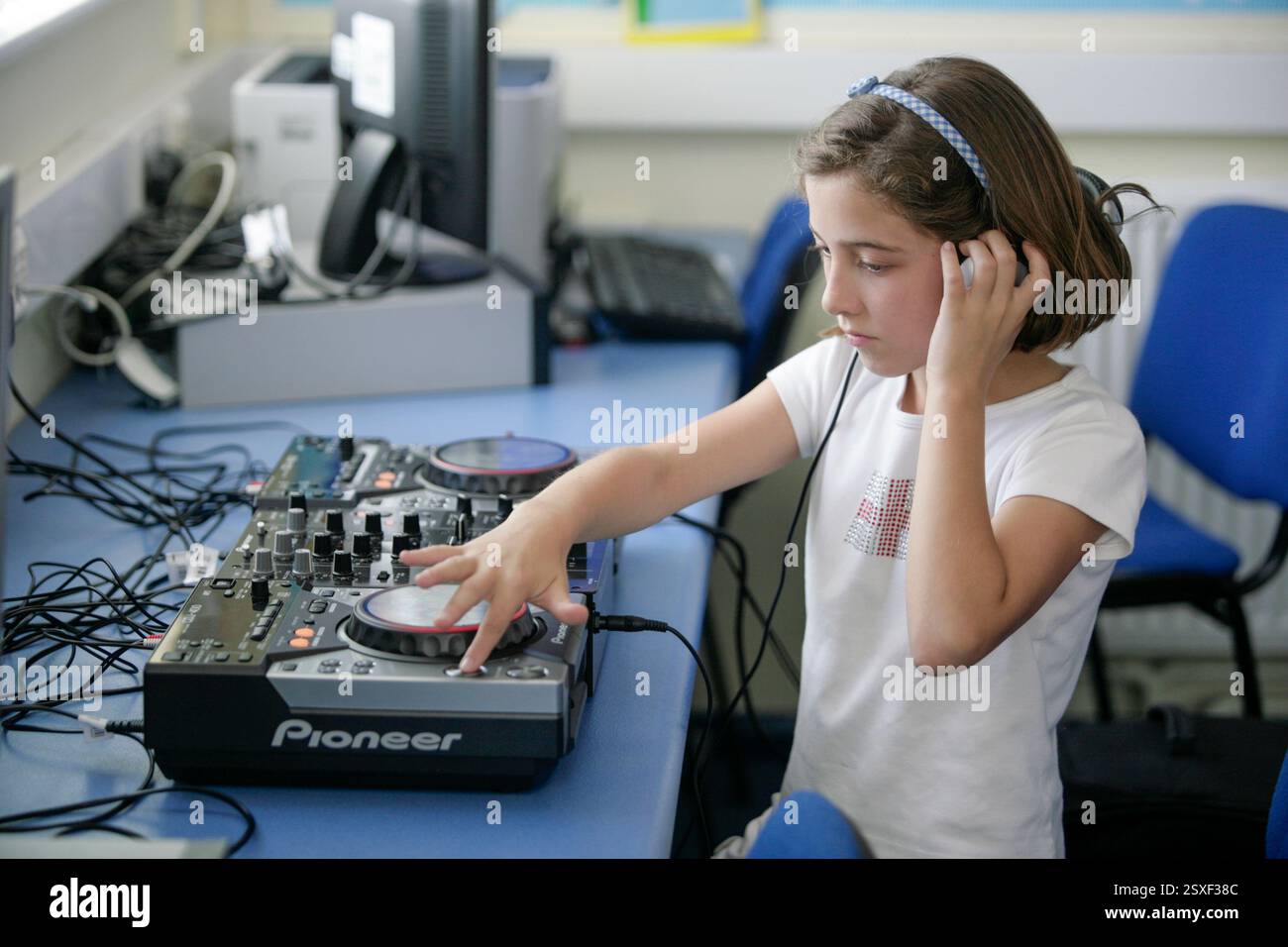 Ein Schulmädchen, das in einem Klassenzimmer einer britischen Schule DJ lernt Stockfoto