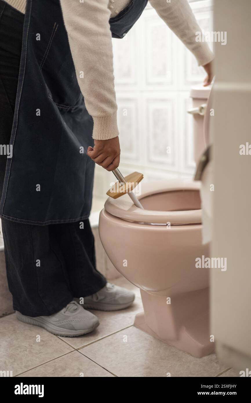 Eine Frau, die die Toilette und das Badezimmer reinigt, perfekt für Inhalte über Reinigung, Hygiene, Haushalt und Hauspflege. Stockfoto