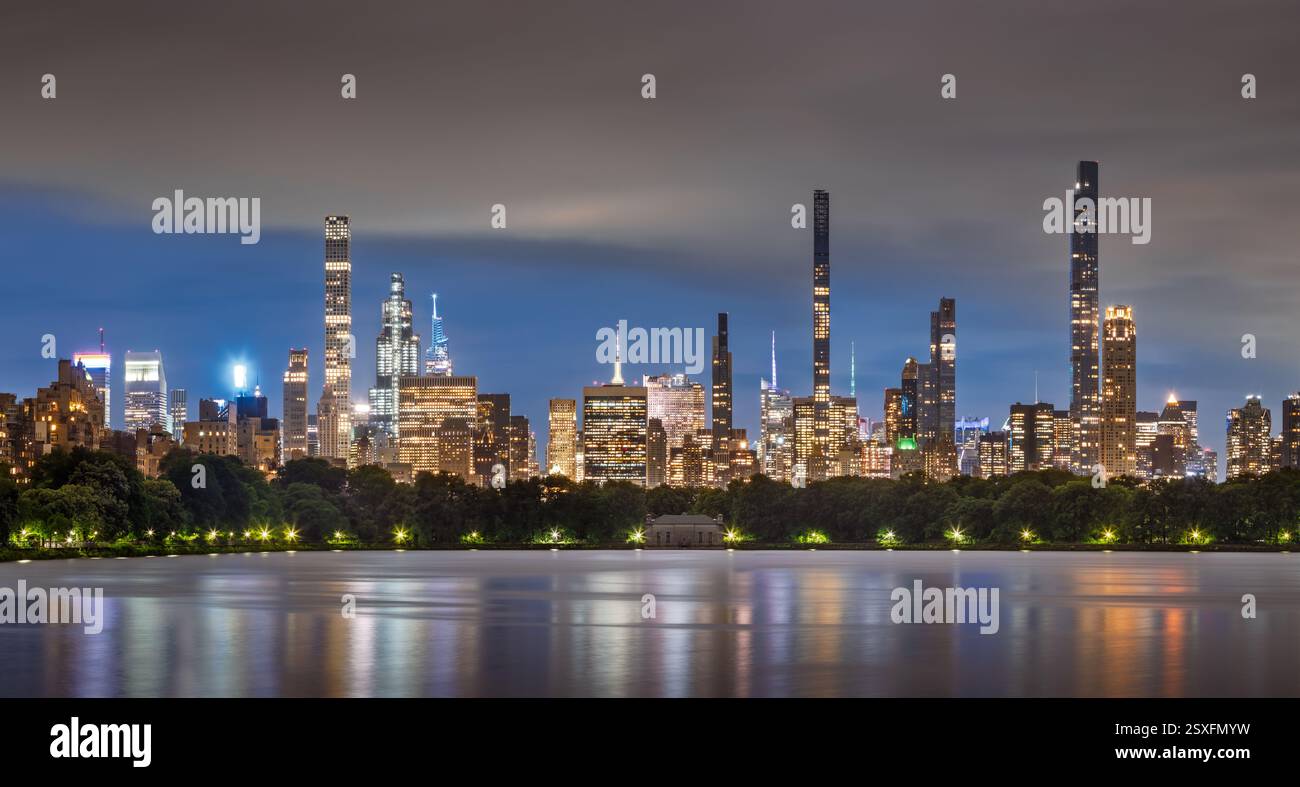 Skyline von New York City bei Nacht mit Reflexen der superhohen Wolkenkratzer der Billionaires Row am Central Park Reservoir. Midtown Manhattan Stockfoto