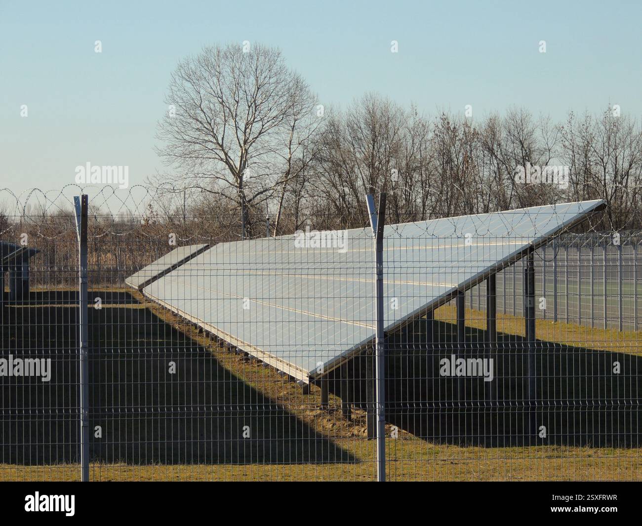 Großes Solarmodul hinter Drahtzaun als Teil der Verarbeitungsanlage, industrielle Stromerzeugung mit Solarpaneelen, Batterie im Solarkraftwerk Stockfoto