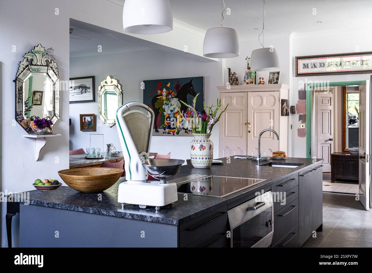 Venezianischer Spiegel und altmodische Küchenwaagen auf Granitkücheninsel in Bayfield Hall, einem renovierten Landhaus aus dem 18. Jahrhundert in Norfolk, Großbritannien. Stockfoto