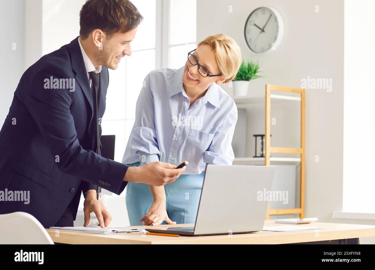 Männliche, weibliche positive Kollegen im Büro, die an einem Projekt am Laptop arbeiten, kooperieren, tippen, reden Stockfoto