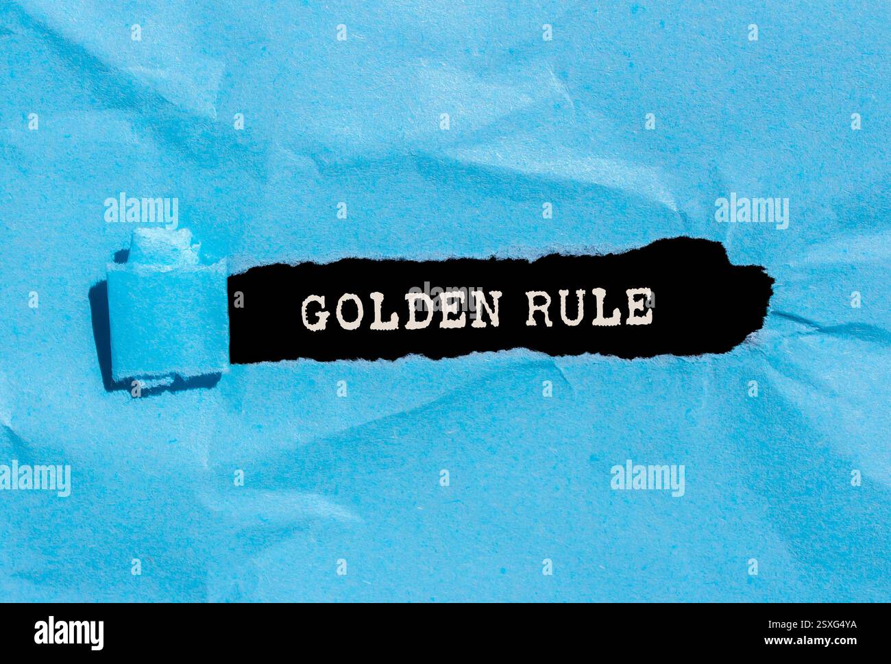 Goldene Regelnachricht auf zerrissenem blauem Papier auf schwarzem Hintergrund. Konzeptionelles goldenes Regelsymbol. Kopierbereich. Stockfoto