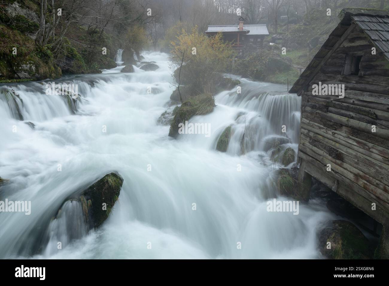 Kaskaden am Fluss Krupa mit hölzernen Wassermühlen, Nebel steigt aus turbulenten Fluss, ruhiger Morgen Stockfoto