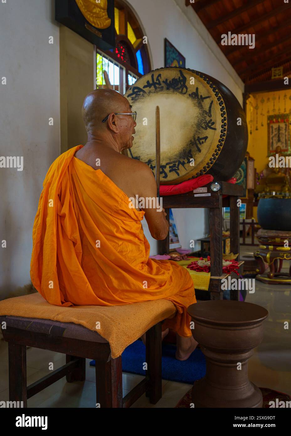 Ein Mönch schlägt die Trommel und singt ein Mantra in einem Meditationszentrum. Stockfoto