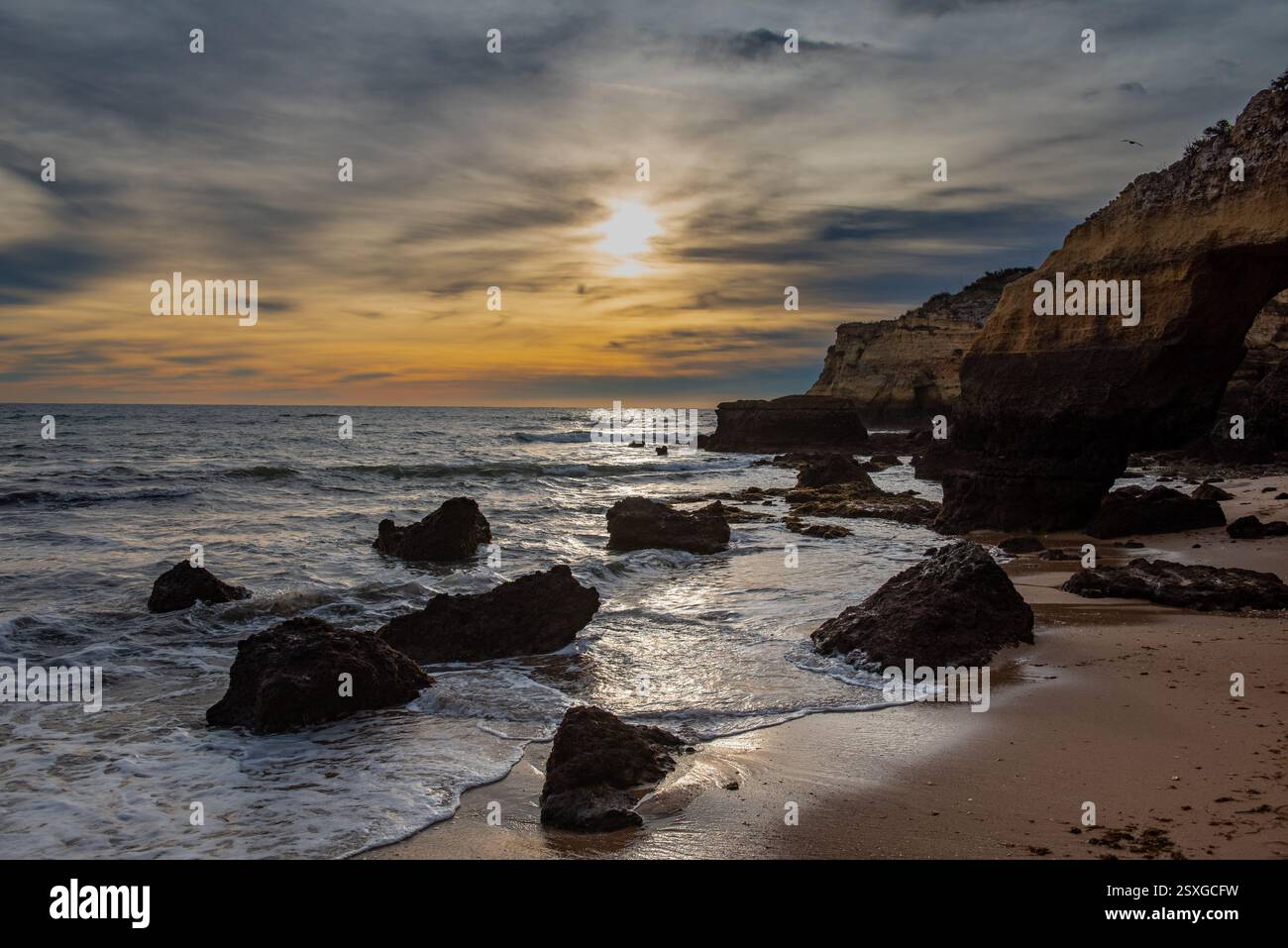 Morgenstrand bei Sonnenaufgang und Felsen im Vordergrund am Strand Praia da Batata in Lagos Portugal mit goldenem Himmel Stockfoto