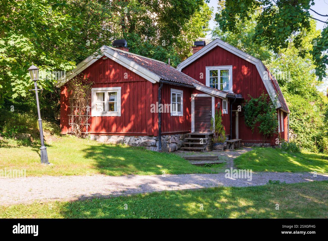 Allgemeiner Blick auf ein typisch schwedisches Falu-Rotes Blockhaus mit einem Gambrel-Dach im Wald an einem sonnigen Sommertag. Stockfoto