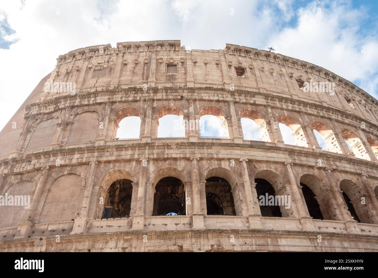Fassade und Äußere des antiken römischen Kolosseums in Rom, Italien mit seinen Bögen an einem sonnigen Tag mit weißen Wolken und blauem Himmel Stockfoto