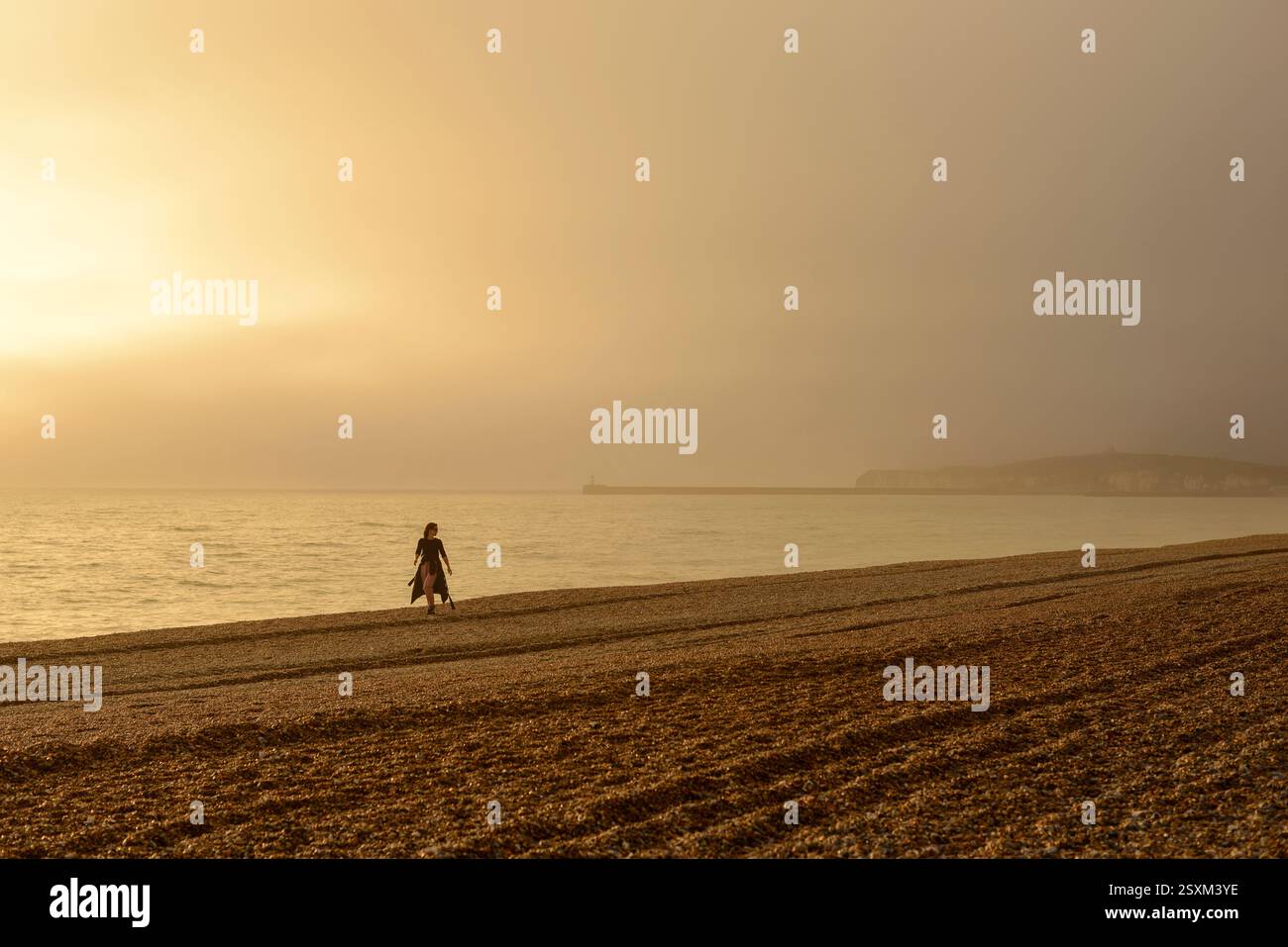 Frau am steinigen Strand, Seaford, East Sussex, Großbritannien, mit Meeresnebel im Februar, Winternachmittag. Stockfoto