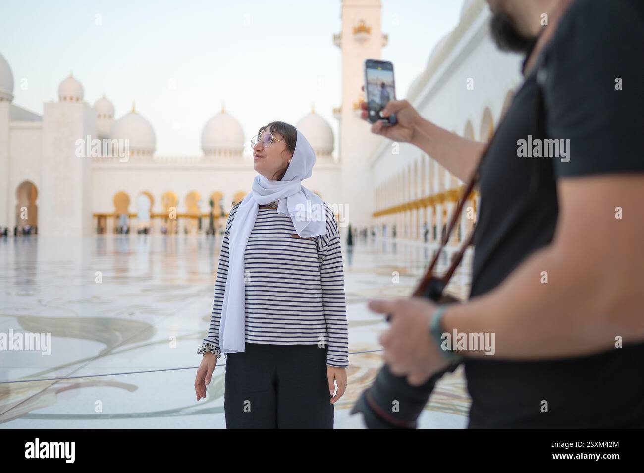 Ein Fotograf fotografiert eine Frau in einem Kopftuch mit ihrem Handy in der Scheich-Zayed-Moschee. Freunde, die Abu Dhabi besuchen und M Stockfoto