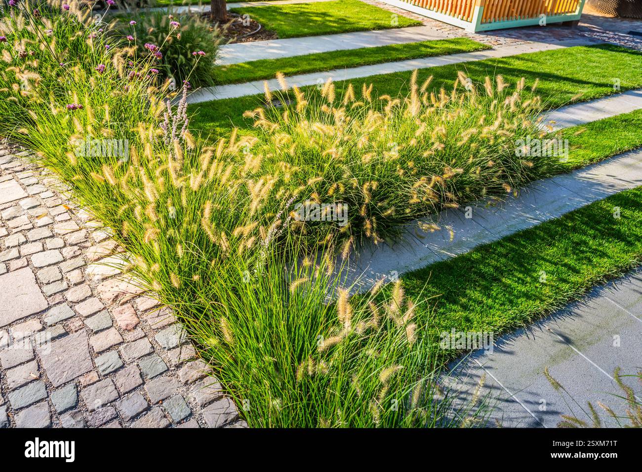 Detail des Gartenweges mit Steinplatten mit Rindenmulch und einheimischen Pflanzen. Landschaftsbau- und Gartenkonzept. Stockfoto