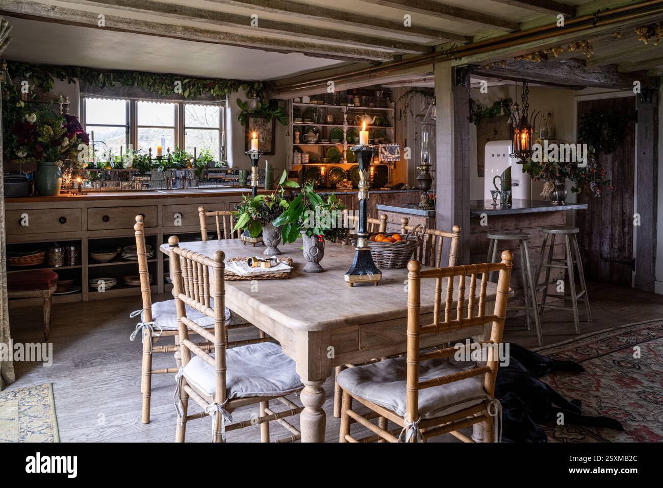 Beleuchtete Kerzen auf Holzküchentisch in renoviertem Bauernhaus East Sussex Tudor aus dem Jahr 1540, England, Großbritannien. Stockfoto
