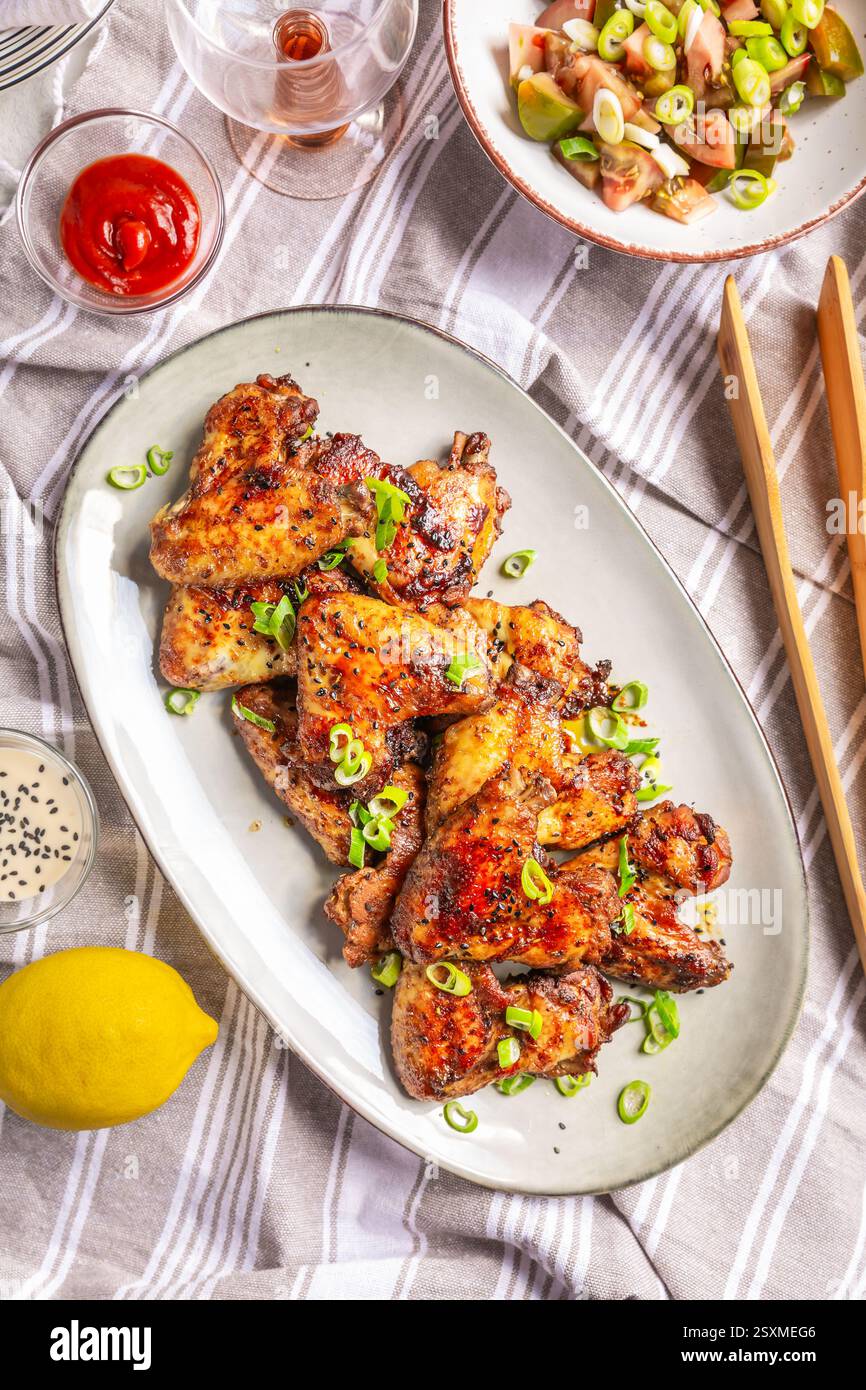 Picknicktisch und Essen im Freien, Hähnchenflügel mit gemischtem Salat Stockfoto